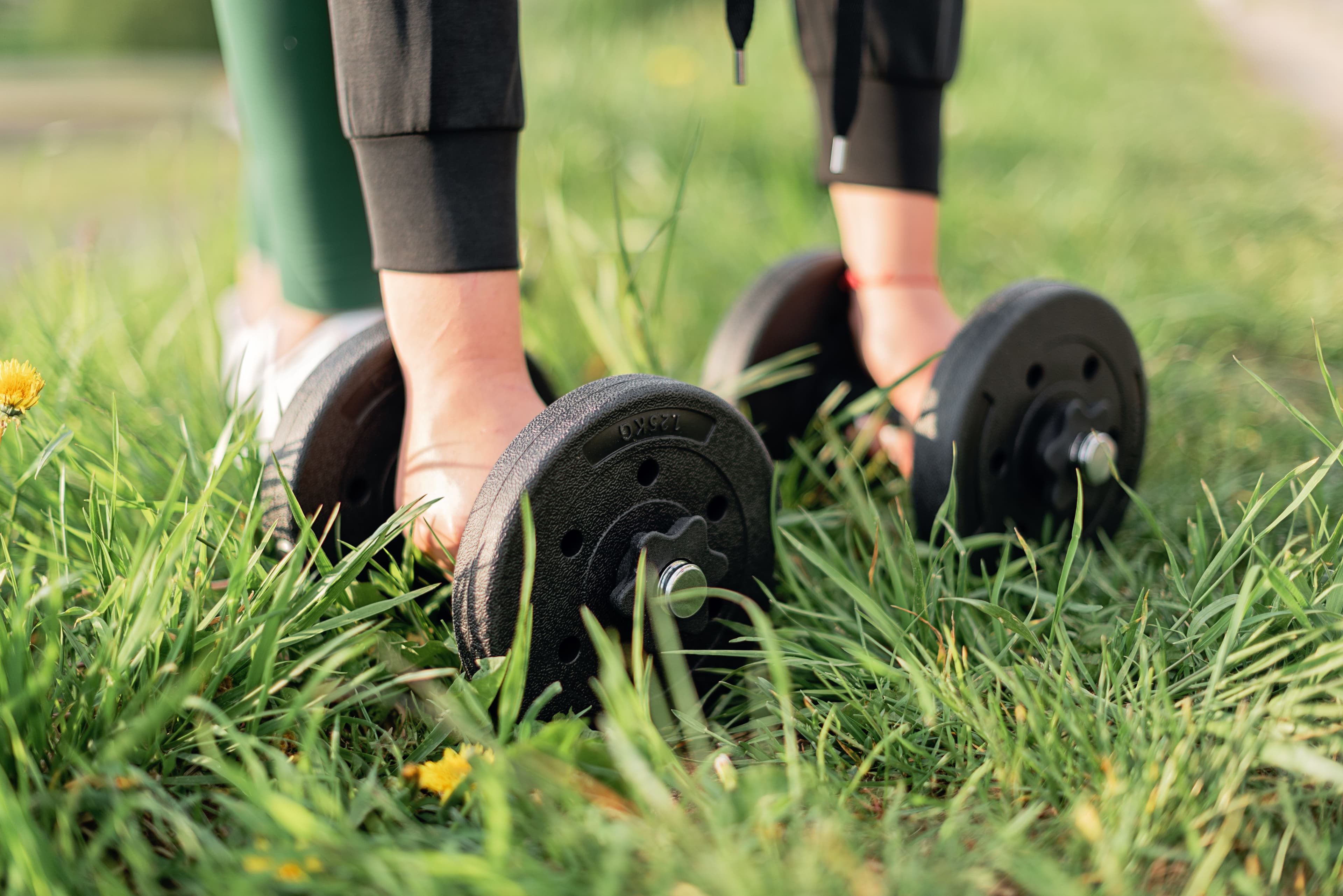 Person exercising outdoors with dumbbells on grass