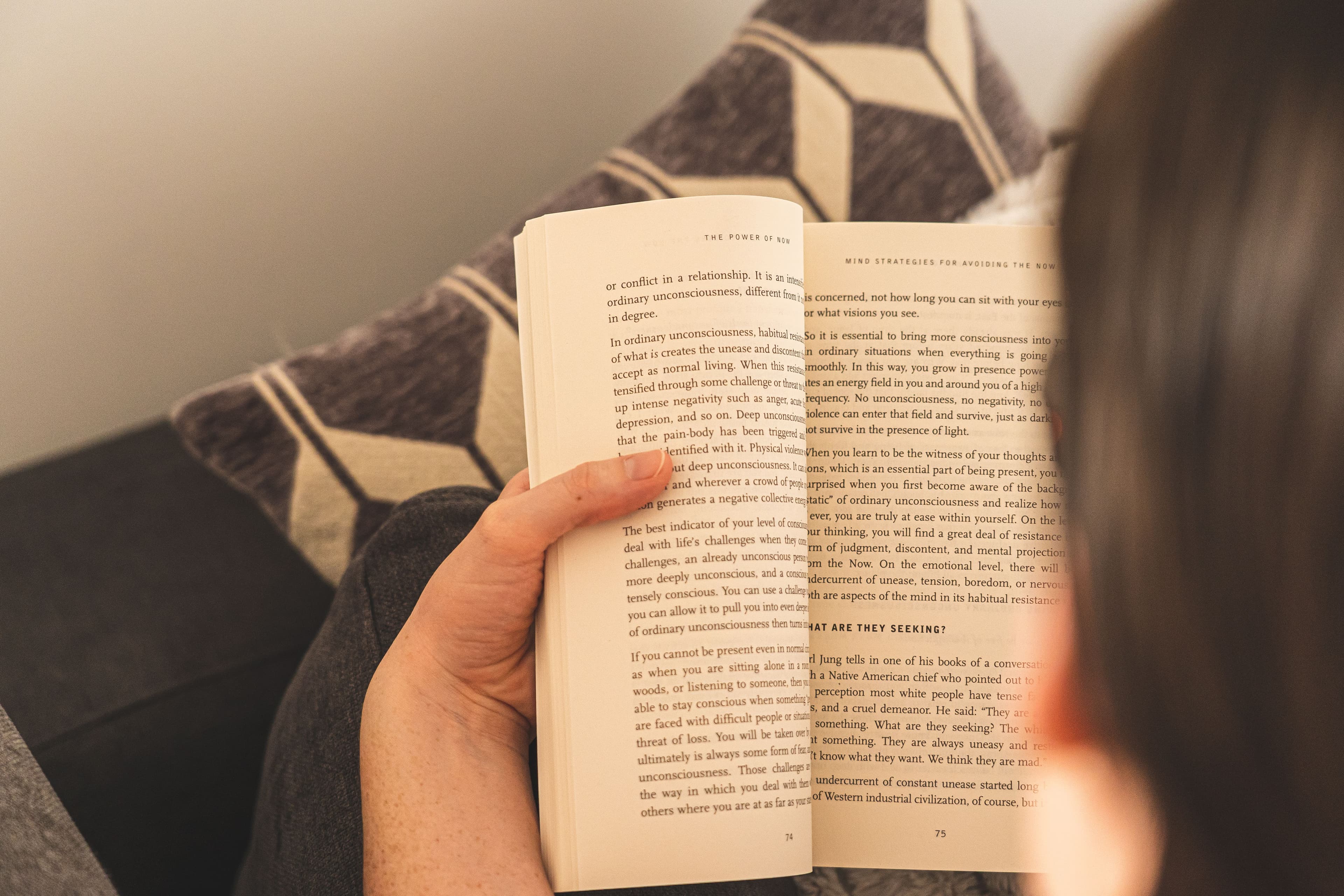 Person reading a book on a couch