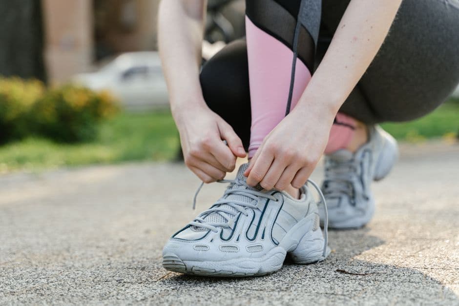 Person tying running shoes before restarting an exercise habit