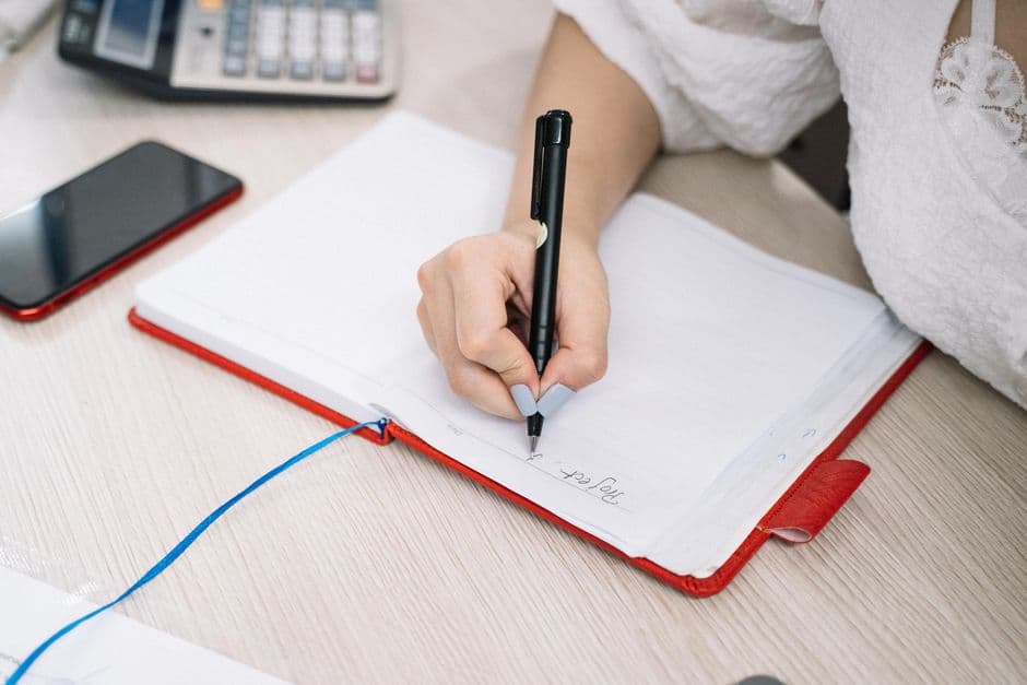 Person writing a habit plan in a notebook